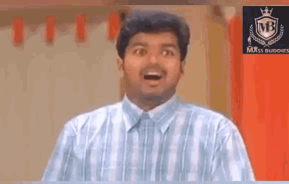 a man in a blue and white striped shirt is making a funny face with his mouth open .