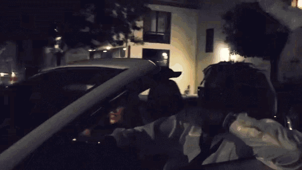 a man and a woman are sitting in a car with a burger king sign in the background