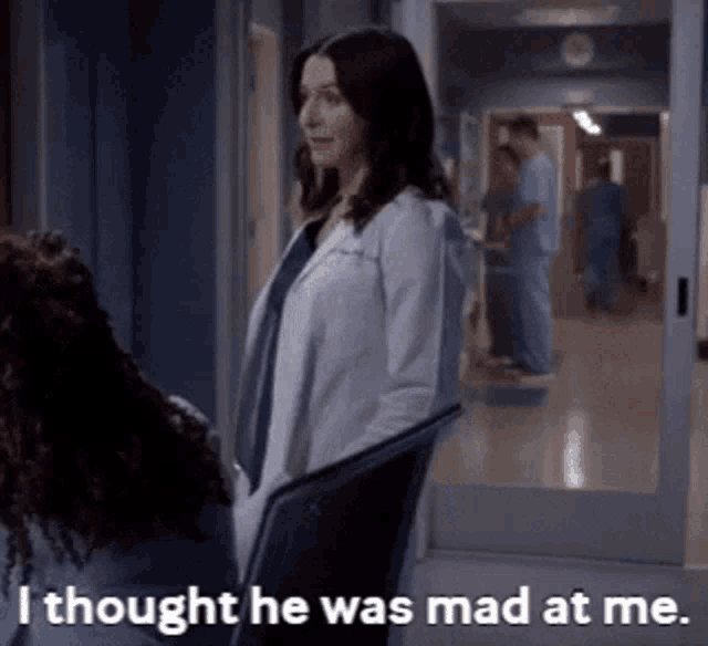 a woman in a lab coat is talking to another woman in a hospital hallway and says i thought he was mad at me .