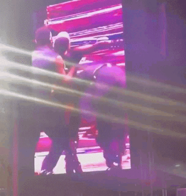 a man is standing on a stage in front of a large screen .