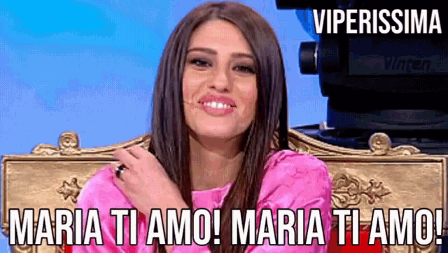 a woman in a pink dress is sitting in front of a video camera with the caption maria ti amo