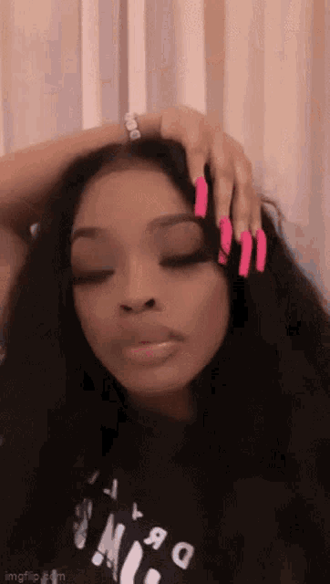 a woman with long pink nails is putting her hand on her hair .