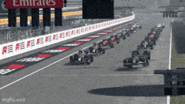 a row of race cars on a track with an emirates sign in the background