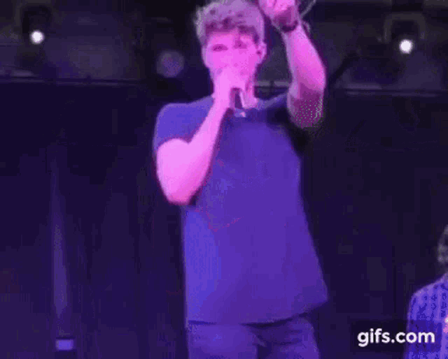 a man is standing on a stage holding a microphone and laughing .