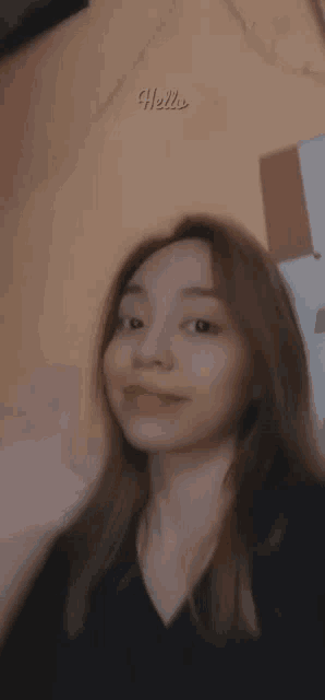 a blurry photo of a woman with the word hello written on the wall behind her