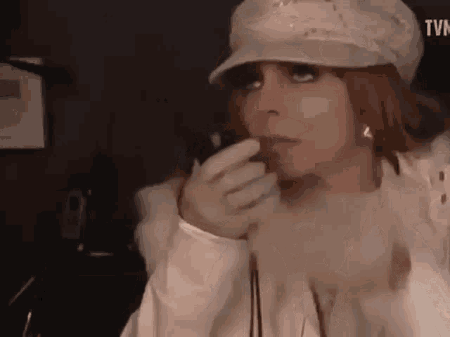 a woman wearing a hat and gloves is holding a microphone in her hand .