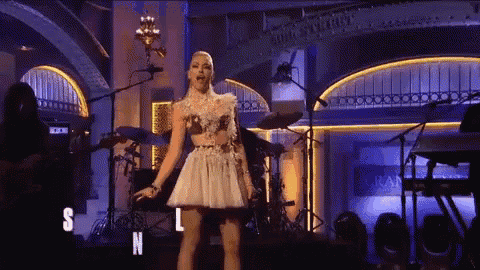 a woman in a white dress is singing on stage in front of a microphone .