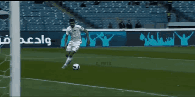 a man kicking a soccer ball on a field with a sign that says ' wadi ' on it