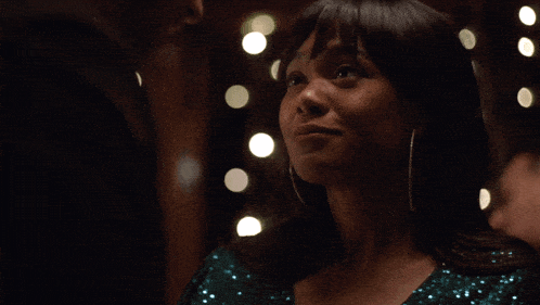 a woman in a green sequined dress smiles in front of lights
