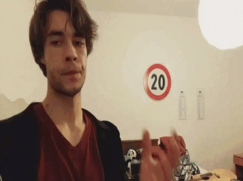a young man is standing in front of a sign that says 20 on it .