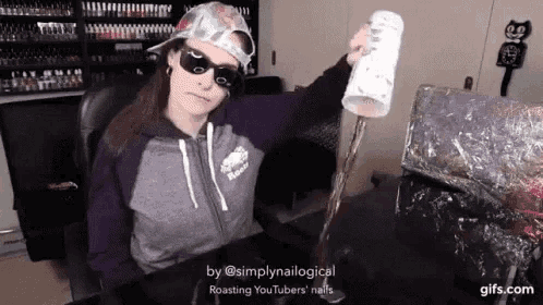 a woman wearing sunglasses and a hat is sitting at a desk holding a paper towel roll .