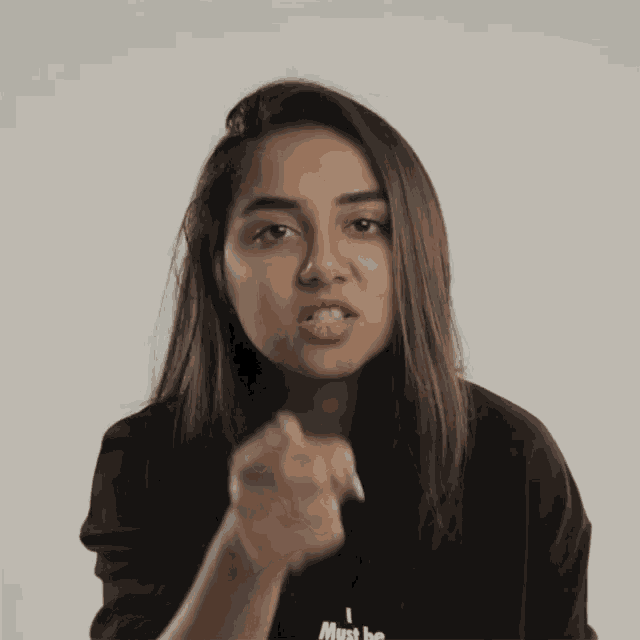 a woman wearing a black shirt that says " i must be "