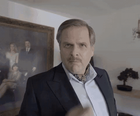 a man in a suit and tie is making a funny face in front of a painting .