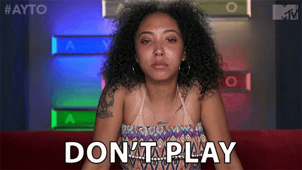 a woman with curly hair is sitting on a couch and saying do n't play