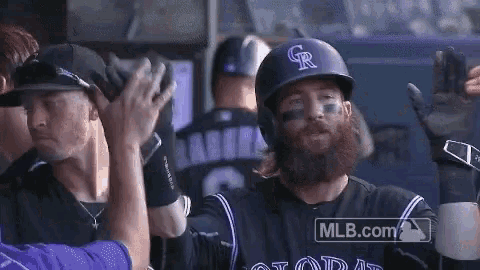 a baseball player with a beard is giving a high five to a teammate .