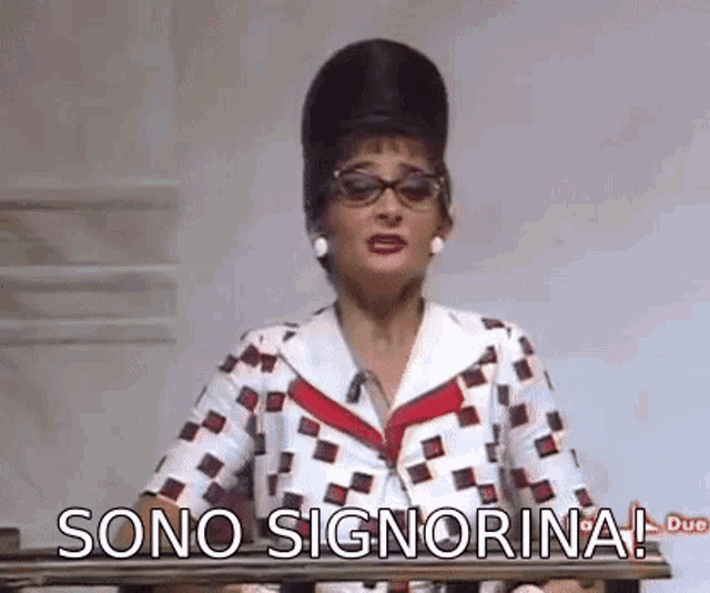 a woman with glasses and a big hat is standing in front of a railing and says sono signorina .