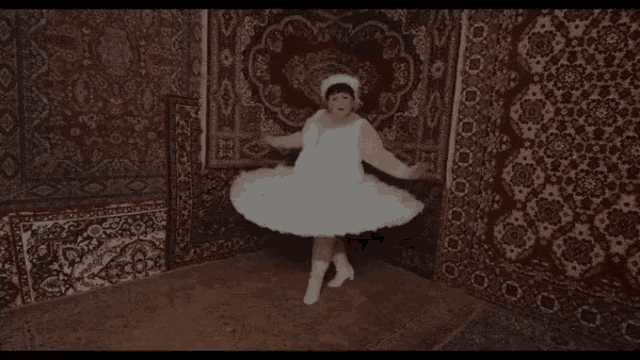 a little girl in a white tutu is dancing in a room with a rug