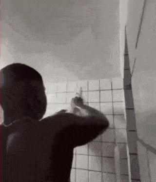 a man is brushing his teeth in a bathroom with white tiles