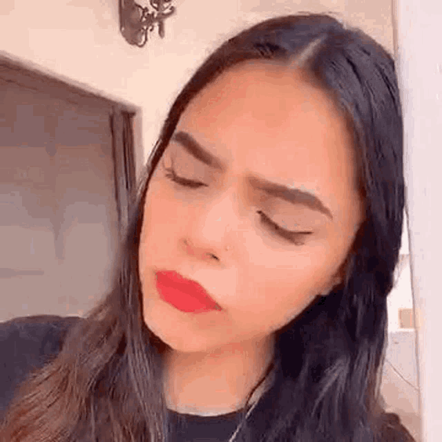 a close up of a woman 's face with her eyes closed and red lipstick on her lips .