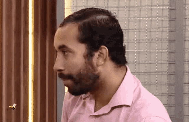a man in a pink shirt is looking at something