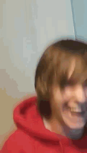 a close up of a person wearing a red hoodie smiling