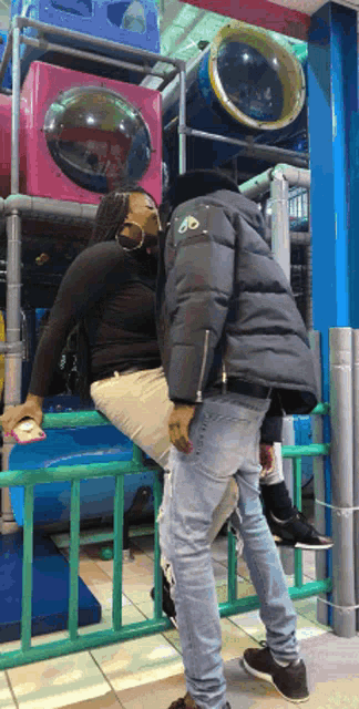 a man wearing a black jacket with the letter d on it kisses a woman
