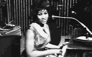 a black and white photo of a woman singing into a microphone