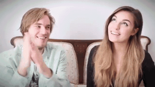 a man and a woman are sitting next to each other on a couch and smiling at each other .