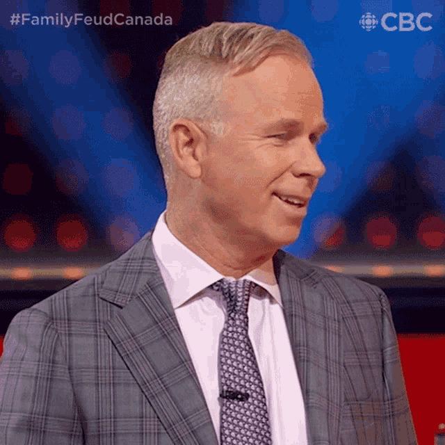 a man in a suit and tie stands in front of a blue background with the letters cbc on it