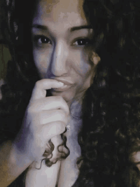 a woman with curly hair is taking a selfie with her hand on her chin