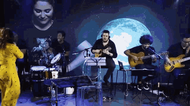 a group of people playing instruments on a stage with a woman singing in the background