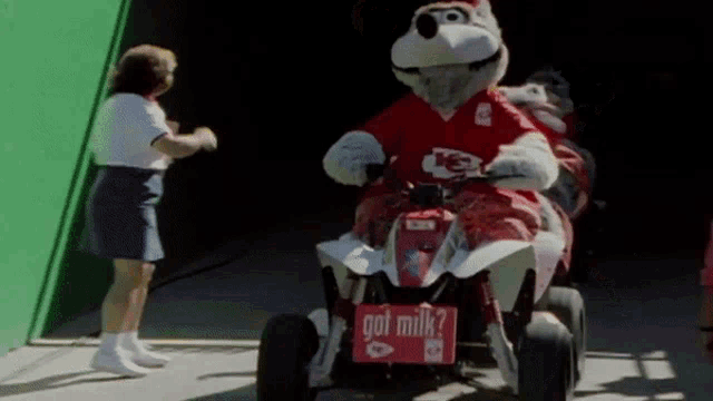 a mascot is riding a four wheeler with a sign that says got milk on it