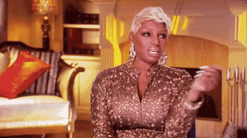 a woman is sitting in a living room wearing a gold dress and earrings .