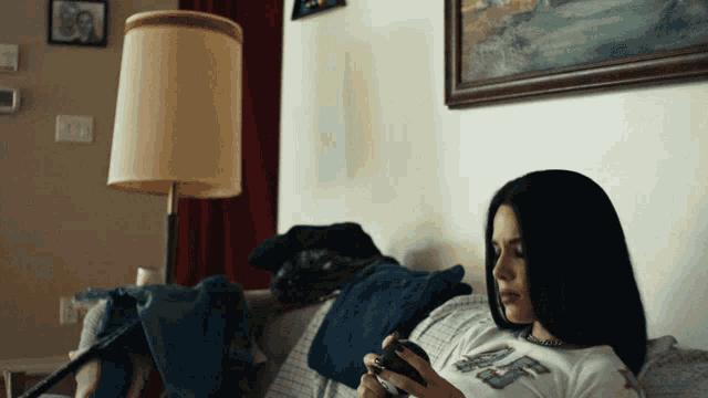 a woman laying on a couch looking at her cell phone