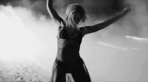a black and white photo of a woman in a bikini dancing in the dark .