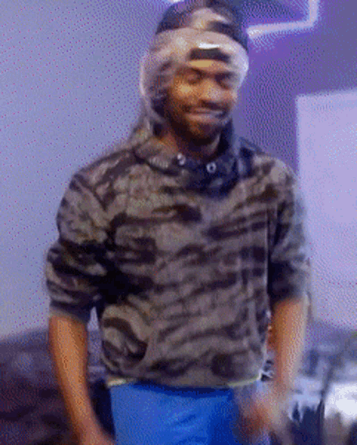 a man wearing a camouflage shirt and blue shorts stands in front of a purple light
