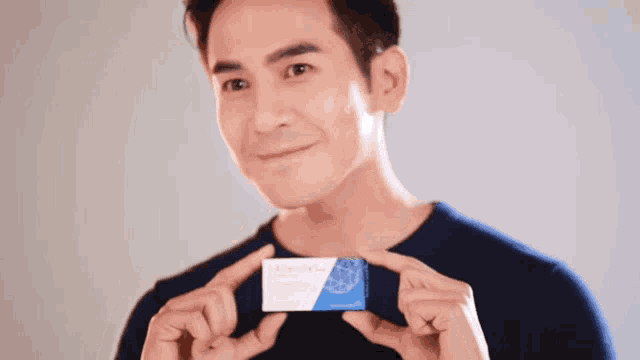 a man in a blue shirt is holding a blue and white box that says ' arginin ' on it