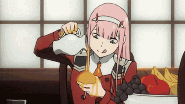 a girl with pink hair is sitting at a table holding a bottle of honey .