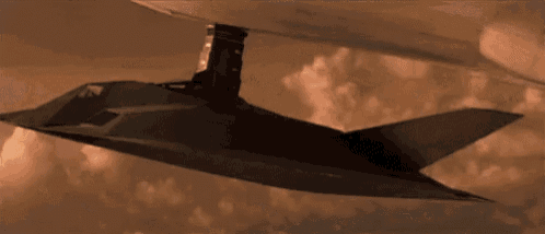 a stealth fighter jet is flying through a cloudy sky next to a plane .