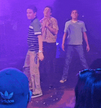a man wearing a blue adidas hat is standing on stage