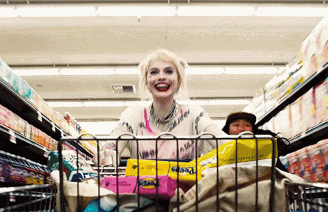 harley quinn is pushing a shopping cart full of diapers