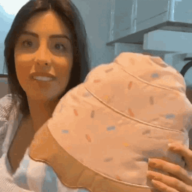 a woman is holding a pillow that looks like a cupcake with sprinkles on it