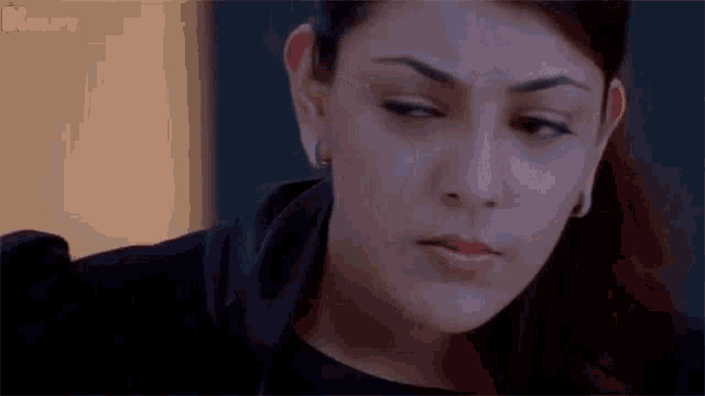 a close up of a woman 's face with her eyes closed and a serious look on her face .