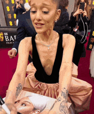 a woman sits on a red carpet in front of a sign that says ee