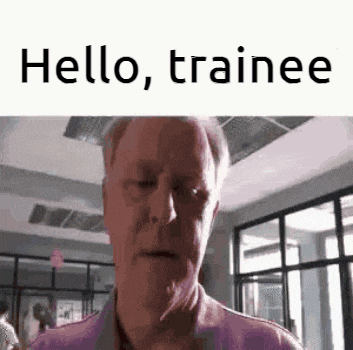 a man is standing in a room with a sign that says `` hello , trainee '' on it .
