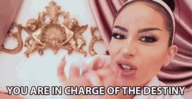 a woman is standing in front of a gold decoration and says `` you are in charge of the destiny '' .