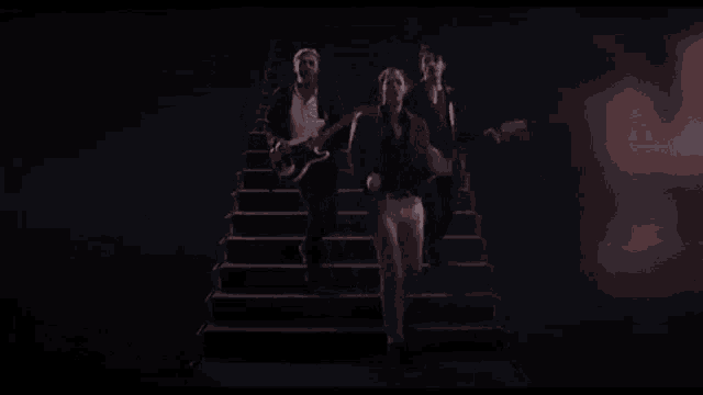a group of men are walking up a set of stairs while playing guitars .