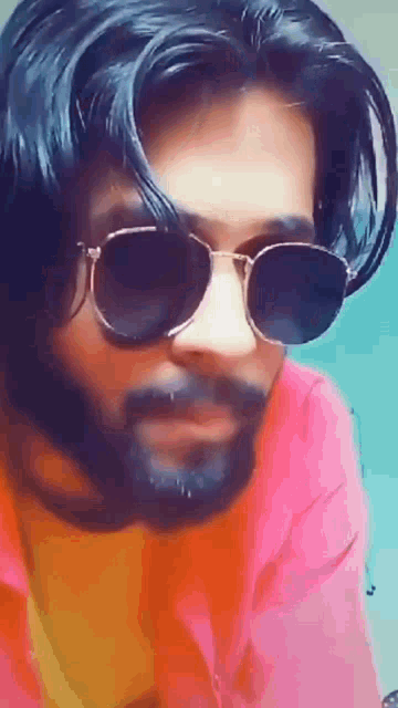 a man with a beard and sunglasses is looking at the camera .