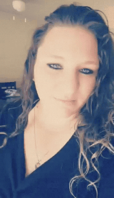 a woman with curly hair and blue eyes is wearing a black shirt
