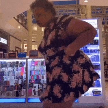 a woman in a floral dress is standing in front of a lush display